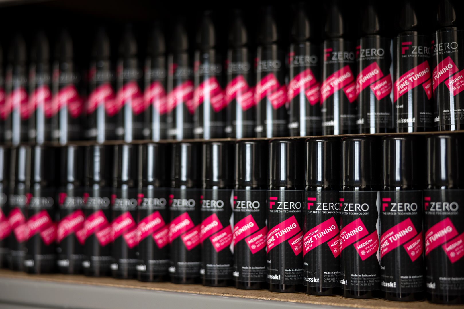 Scaffali pieni di bombolette spray nere con la scritta "F Zero" in rosso. Le bombolette sono etichettate come "Fine Tuning" e "Medium".